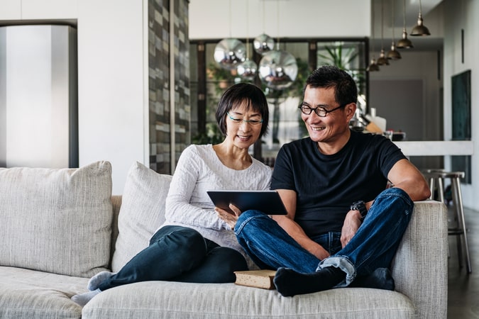 mature couple using digital tablet at home in living room