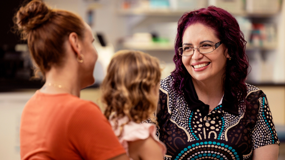 Health practitioner talking to mother and daughter