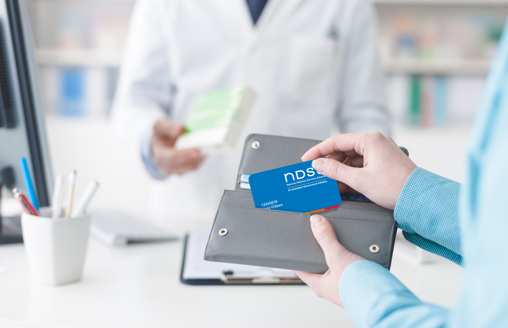 Woman holding NDSS card at chemist checkout