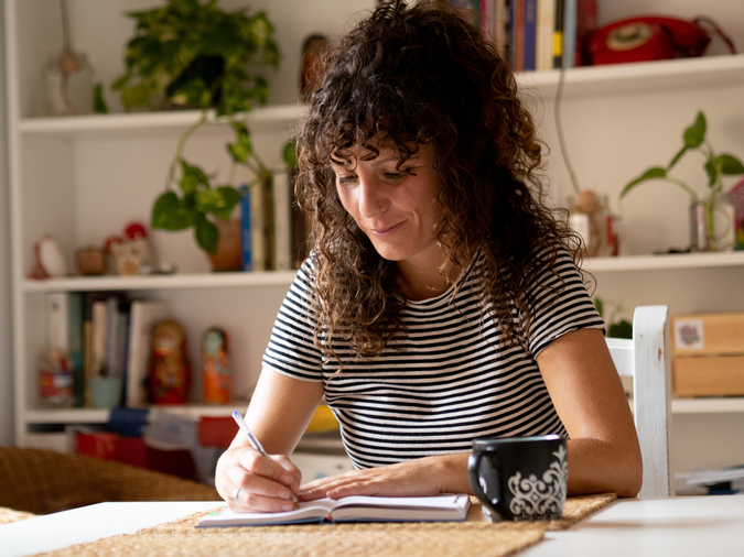 Woman sitting at a table writing in book