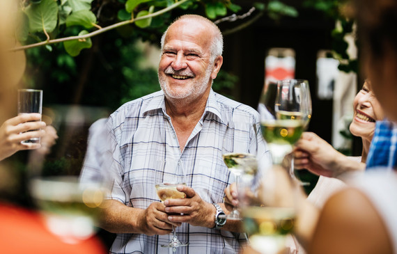 An older man making a toast to his family and friends at a barbecue.