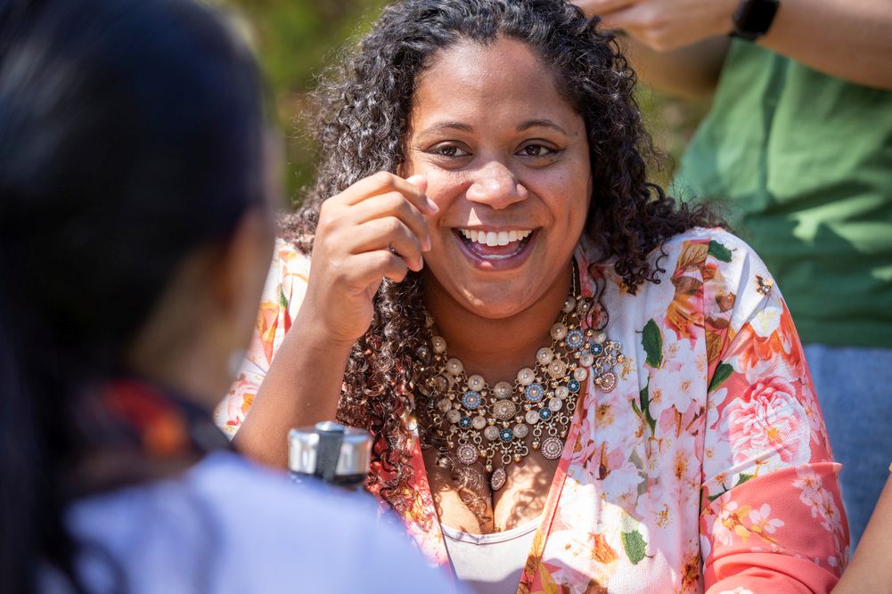 Close up image of a woman sitting down, laughing in a group of people