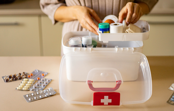 Closeup female hand neatly placing items in a domestic first aid kit
