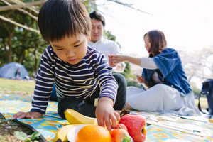 Child reaching for plate of fruit