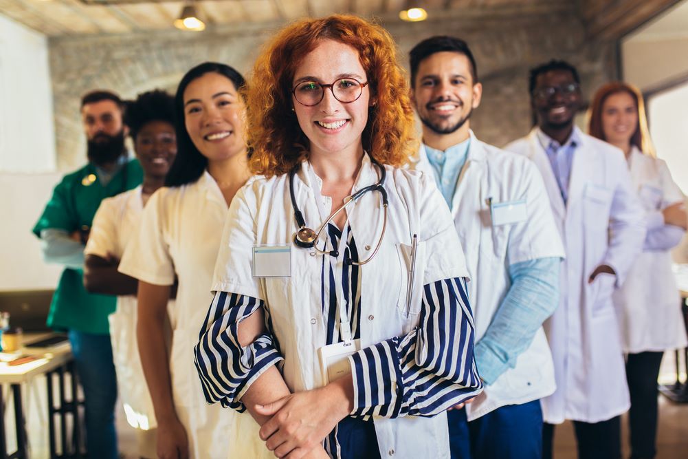 Multiple health care professionals standing in a row, all looking at camera