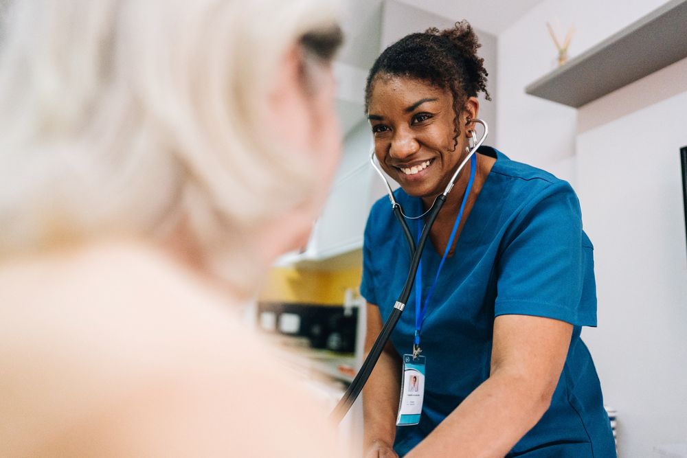 Female health professional using a stethoscope on patient