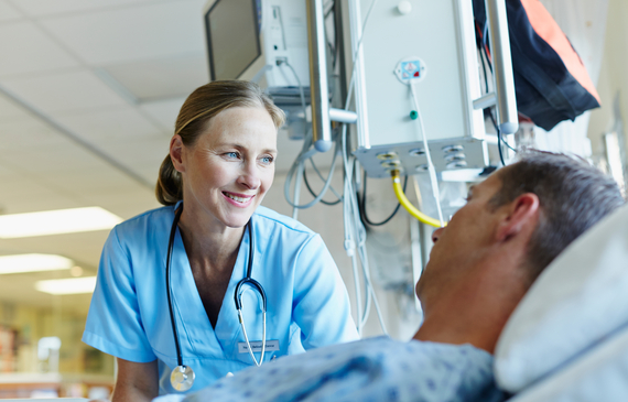 Health professional looking at patient in hospital bed