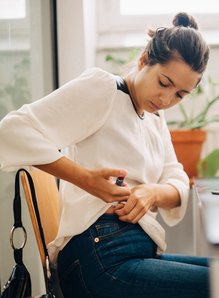 person injecting insulin while sitting at desk