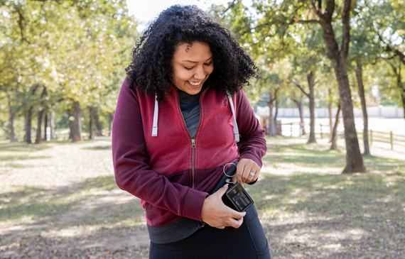 Young woman checks insulin pump and blood sugar monitor while hiking outdoors