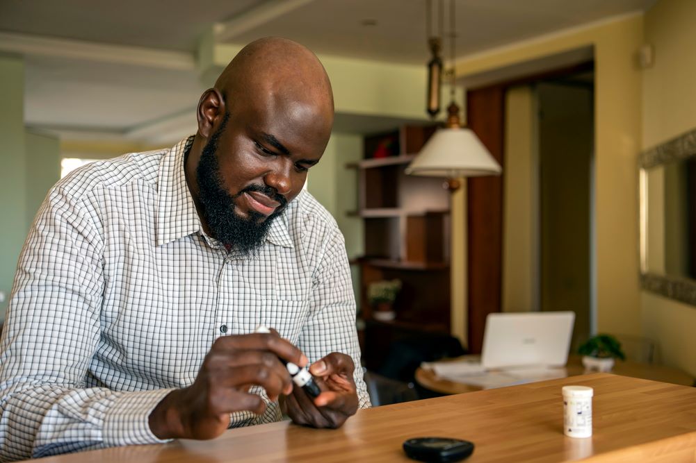 Man sitting at desk at home, using a finger prick check