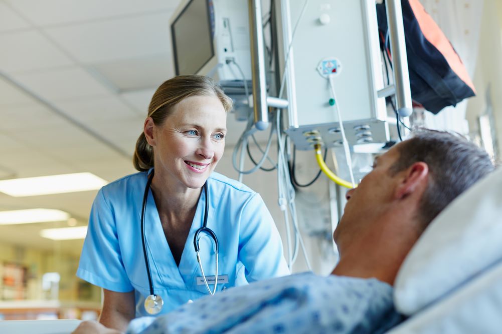 Nurse talking to a patient who is lying in a hospital bed