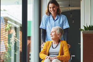 Older woman in wheelchair being pushed by a care worker