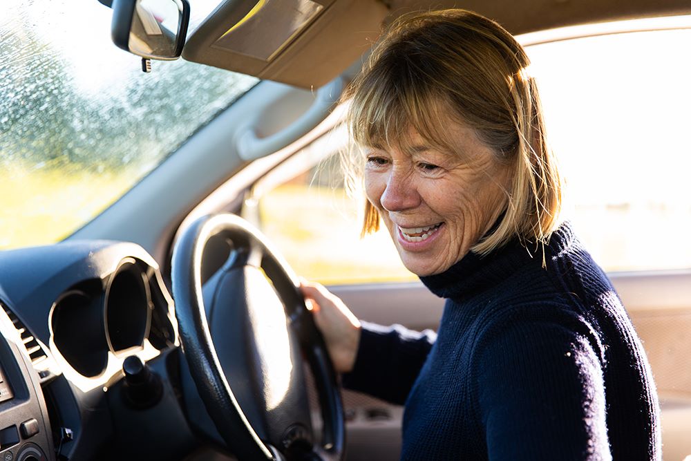Older woman sitting in the driver's seat of a car