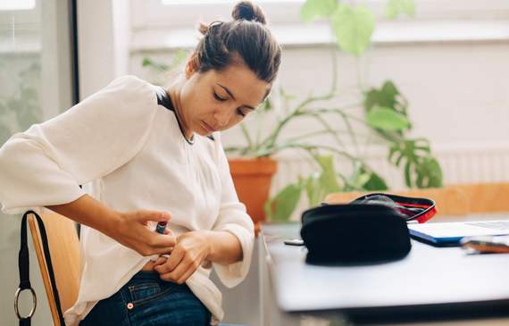 woman injecting insulin while sitting at desk