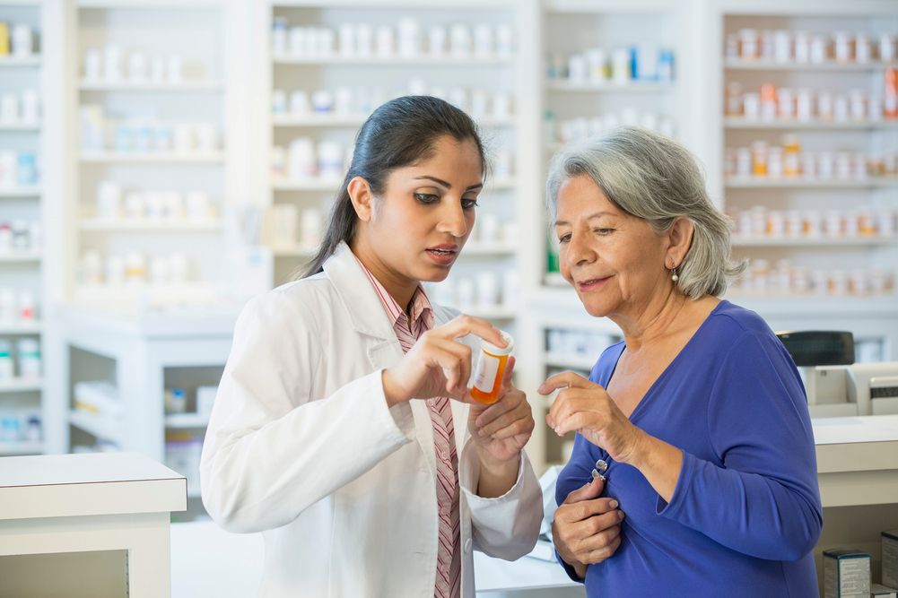 Pharmacist explaining medication to older customer