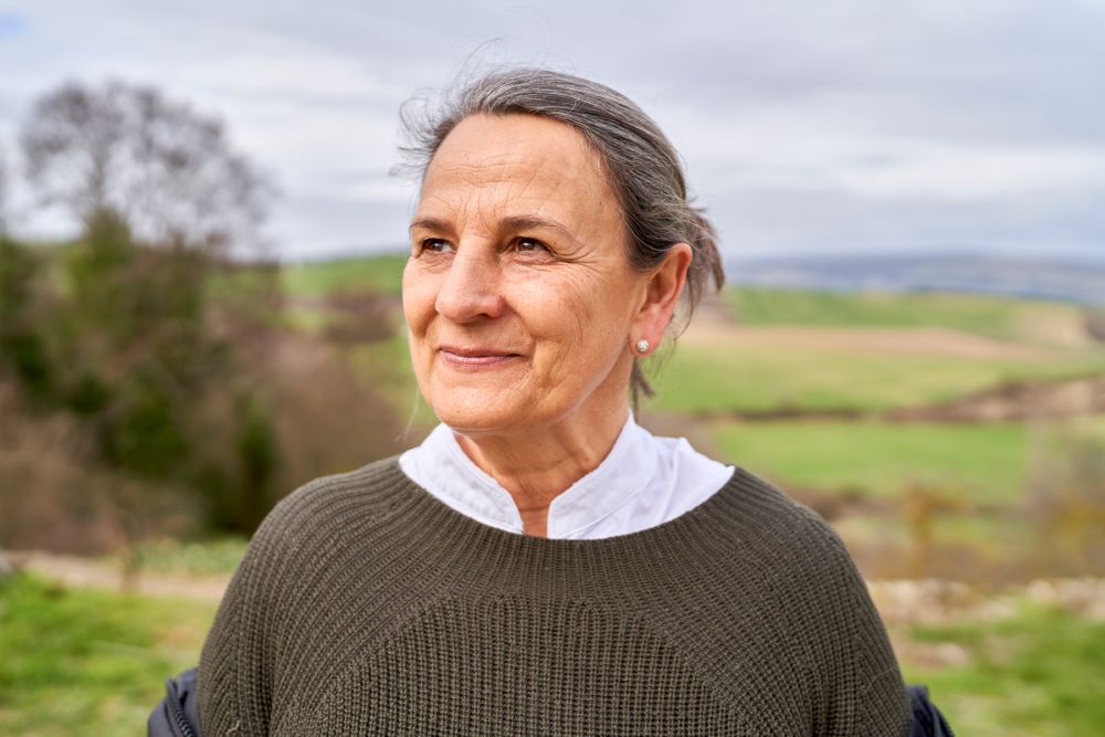 Portrait of older woman, standing in a field