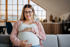 smiling pregnant woman sitting on her sofa
