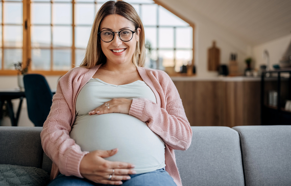 smiling pregnant woman sitting on her sofa