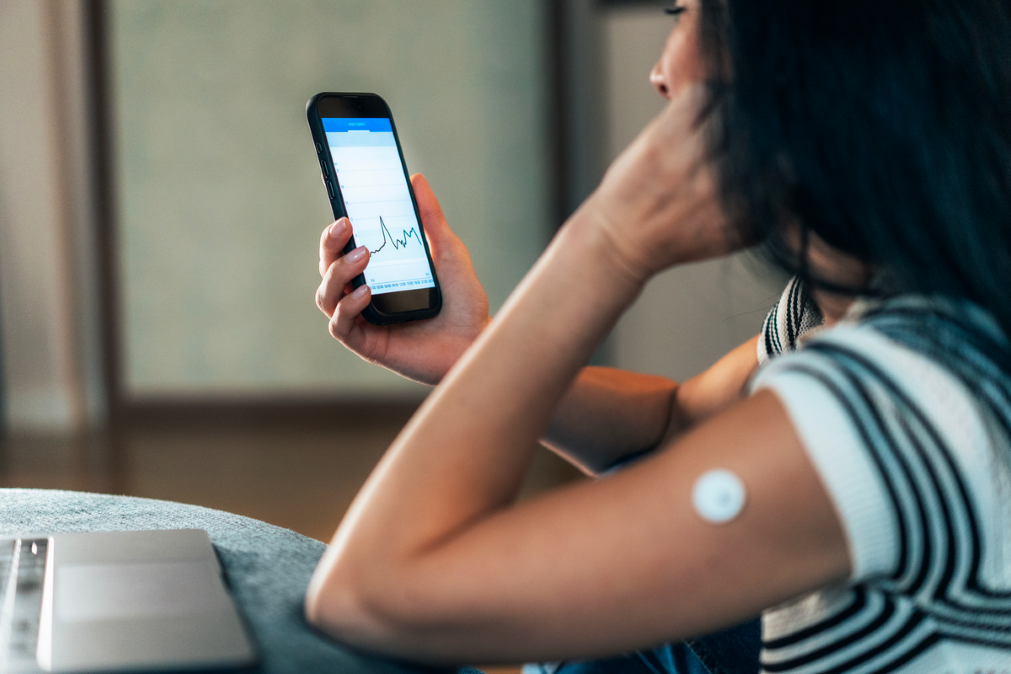 Woman looking at phone to check blood glucose levels