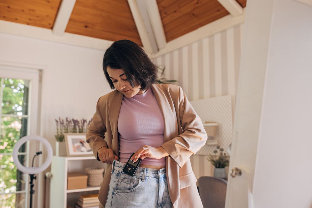 Woman standing in her bedroom, checking her insulin pump