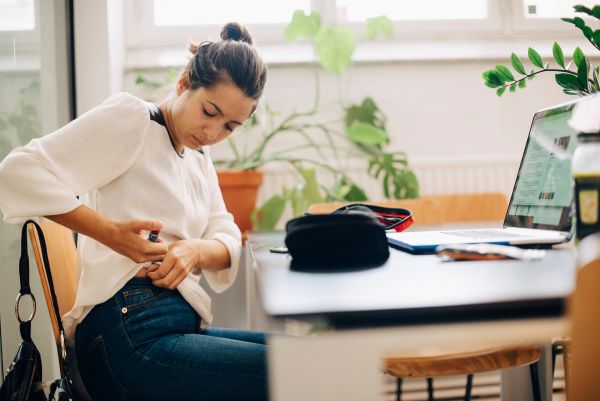 Woman sitting at a desk, using an insulin pen